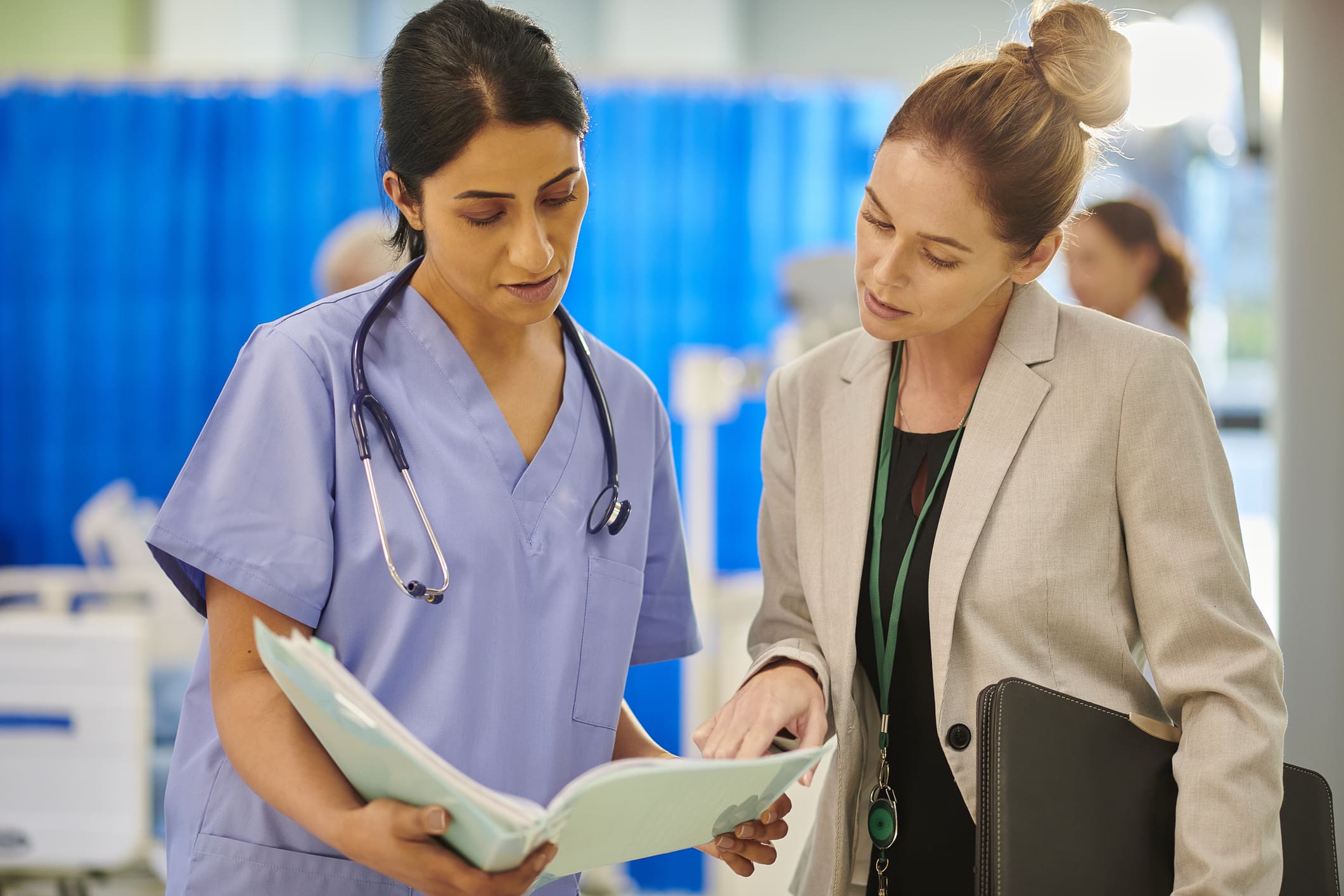 A nurse and a professional review medical documents together.