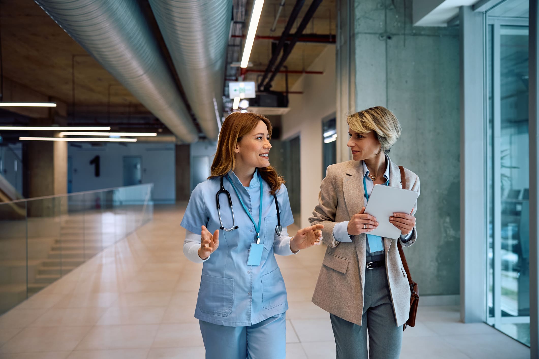 Doctor and professional walking and discussing in hospital hallway.