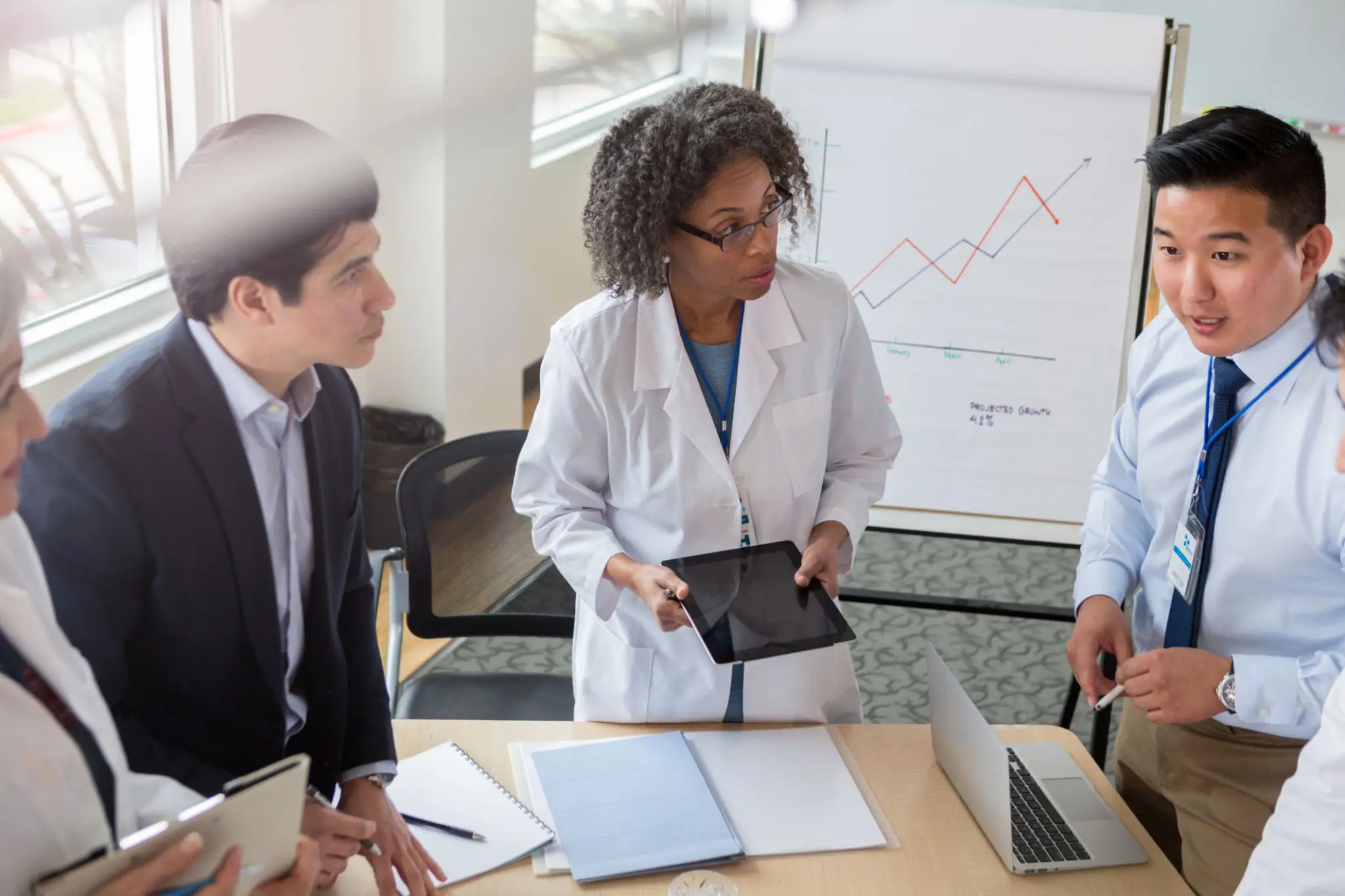 Two professionals discussing data in a meeting room with charts.