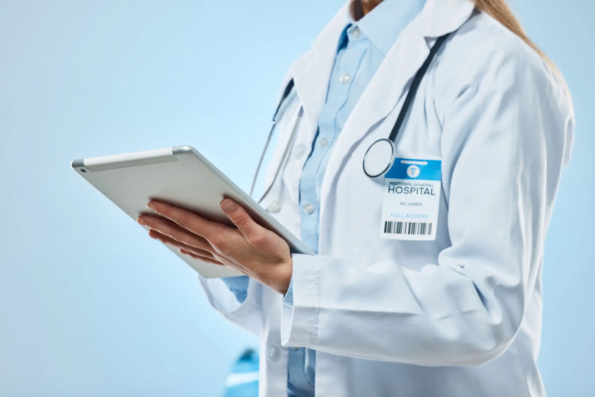 Doctor holding a tablet with a stethoscope around their neck.